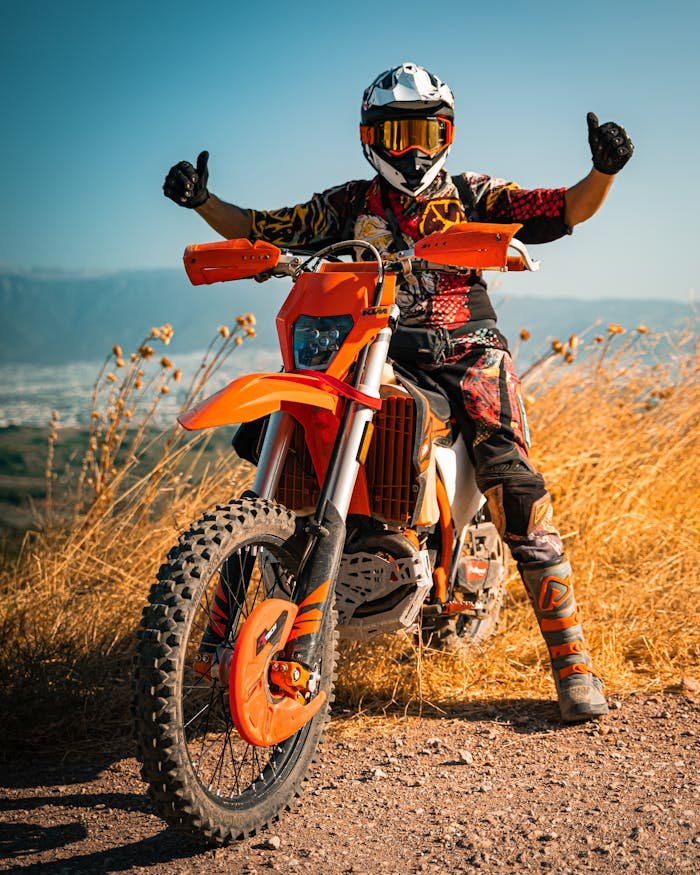 A motocross rider poses with a dirt bike under a clear blue sky in Gündoğdu, Türkiye.